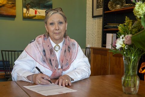 Dianne Taylor-Gearing sitting in her office signing the Dimensions Charter