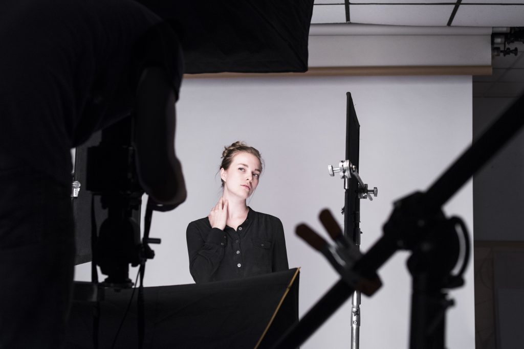 Model dressed in black with her hand placed on her neck, preparing for her photo to be taken.