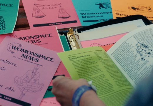 Hands flipping through many copies of Womonspace News zine.