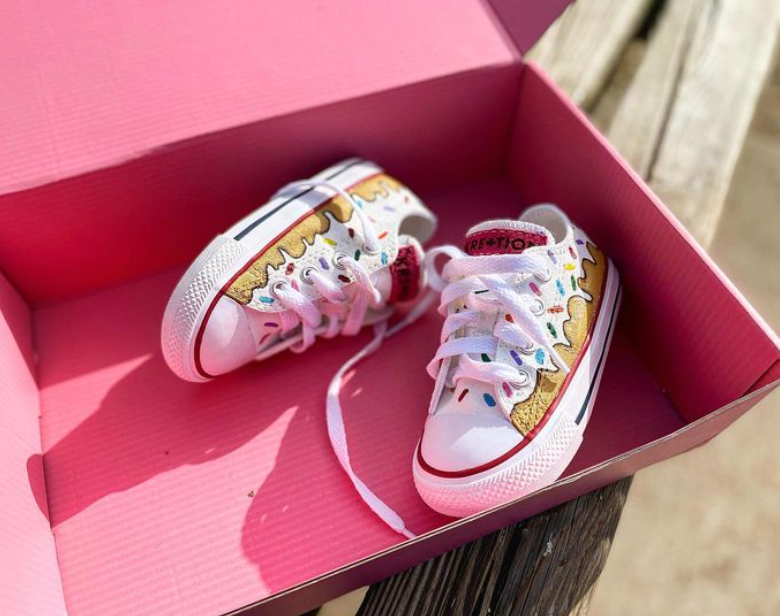 a pair of kid sneakers painted like a donut with sprinkles