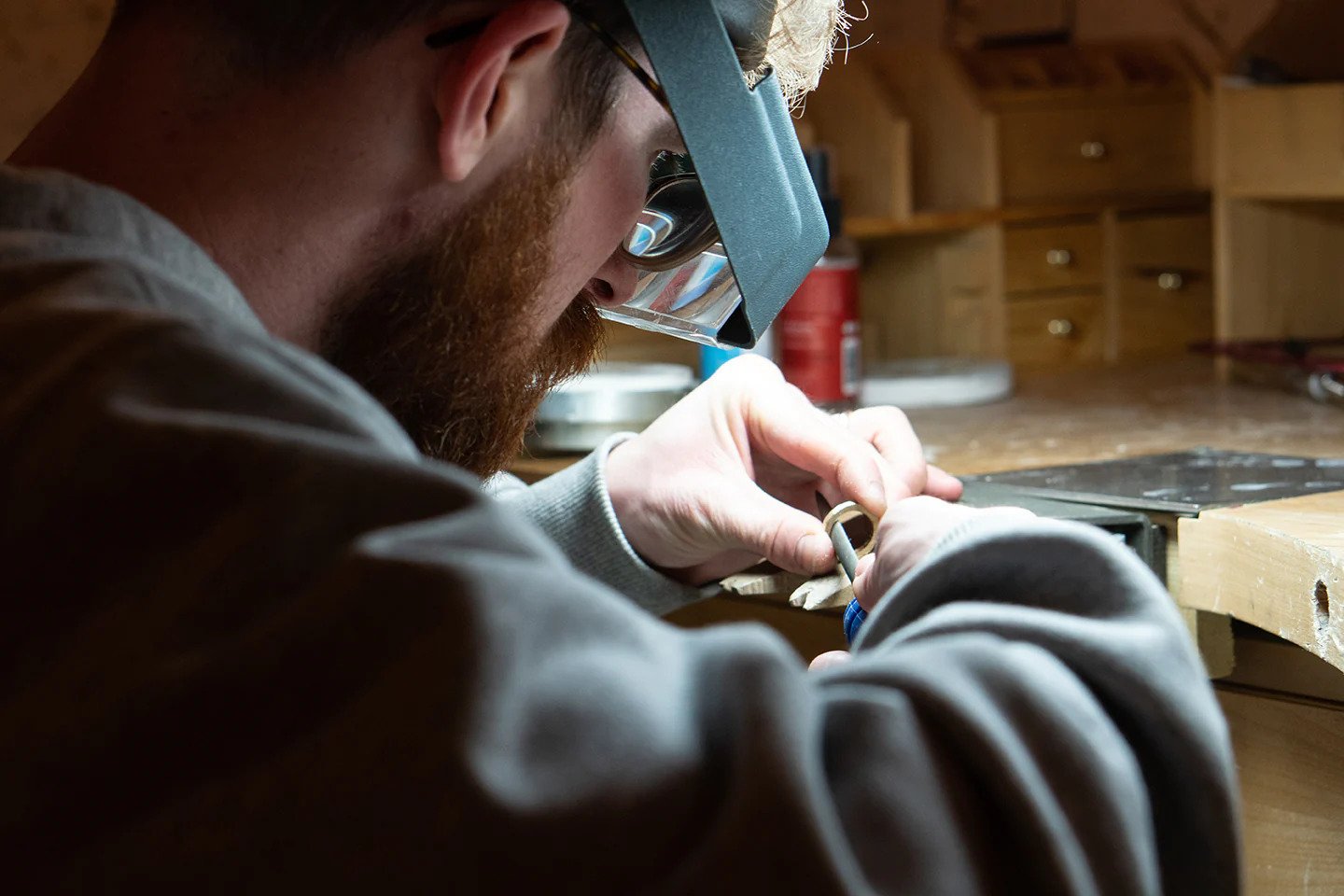 A metalsmith polishes a ring in their workshop.