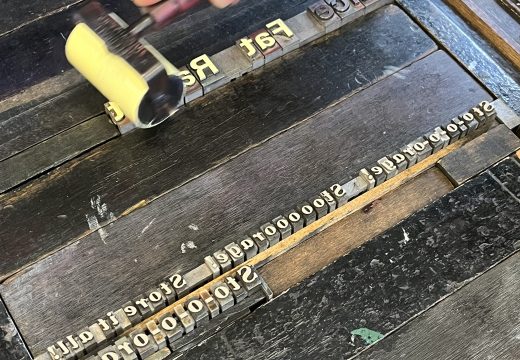 Black ink being rolled onto a letterpress with metal type face