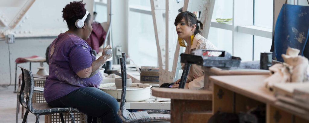 two ceramics students working at the port talking