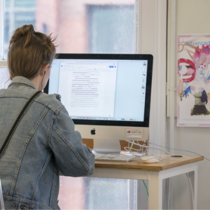A NSCAD student sitting at a computer in the NSCAD Learning Commons.