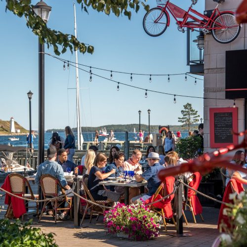 Busy restaurant patio with a red bicycle sculpture on the Halifax waterfront