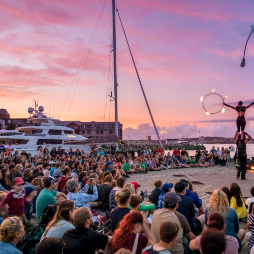Busker performing for a large crowd on the Halifax waterfront at sunset