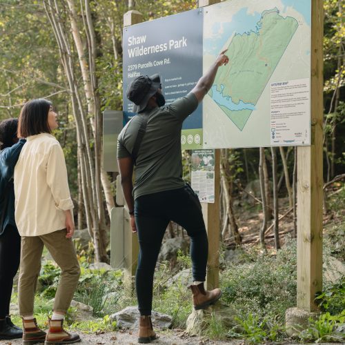 Two people reading a trail map at the start of a coastal hiking trail in Nova Scotia