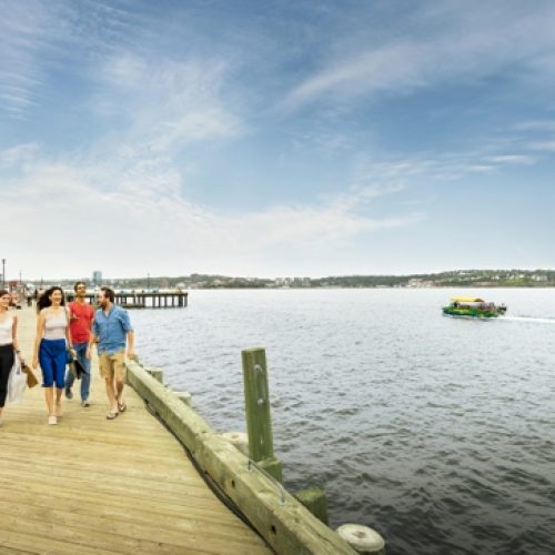 People walking along the Halifax waterfront boardwalk on a sunny day