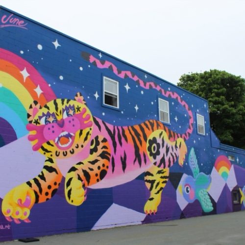 Large colourful mural of a tiger and a rainbow on the side of a building